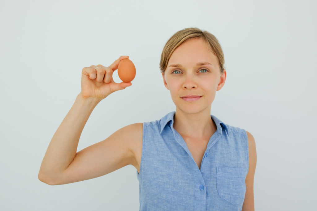 attractive-woman-holding-egg-with-two-fingers