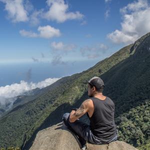 man sitting on top of a mountain after doing exercises for boosting male fertility